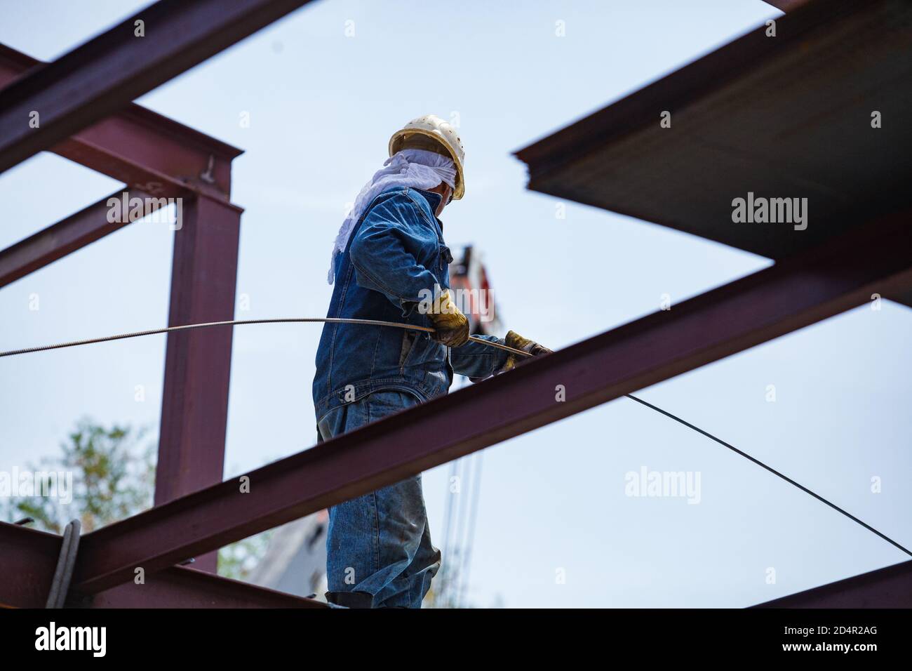 Bauarbeiter in gelber Harthut mit Stahlarmierungsstab. Kein Gesicht des Arbeiters. Stockfoto