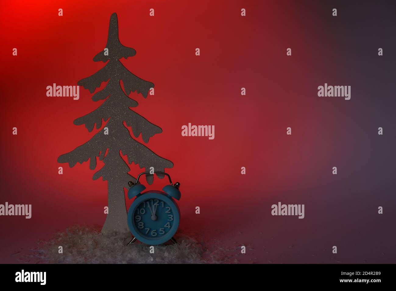 Weihnachtsbaum mit einem blauen Wecker auf einem roten Hintergrund- und Kopierbereich Stockfoto