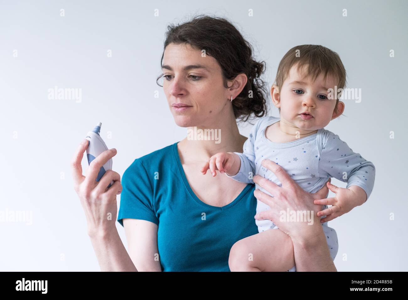 Mutter verwendet ein Ohrthermometer, um die Temperatur ihrer 15 Monate alten Tochter zu messen. Stockfoto