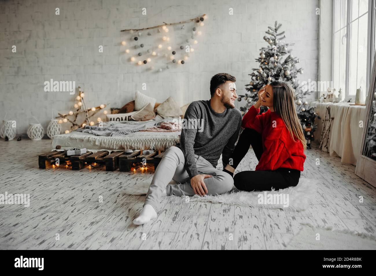 Junges Paar feiert Weihnachten verbringt Zeit zusammen zu Hause, während auf dem Boden sitzen. Frohe Weihnachten Stockfoto