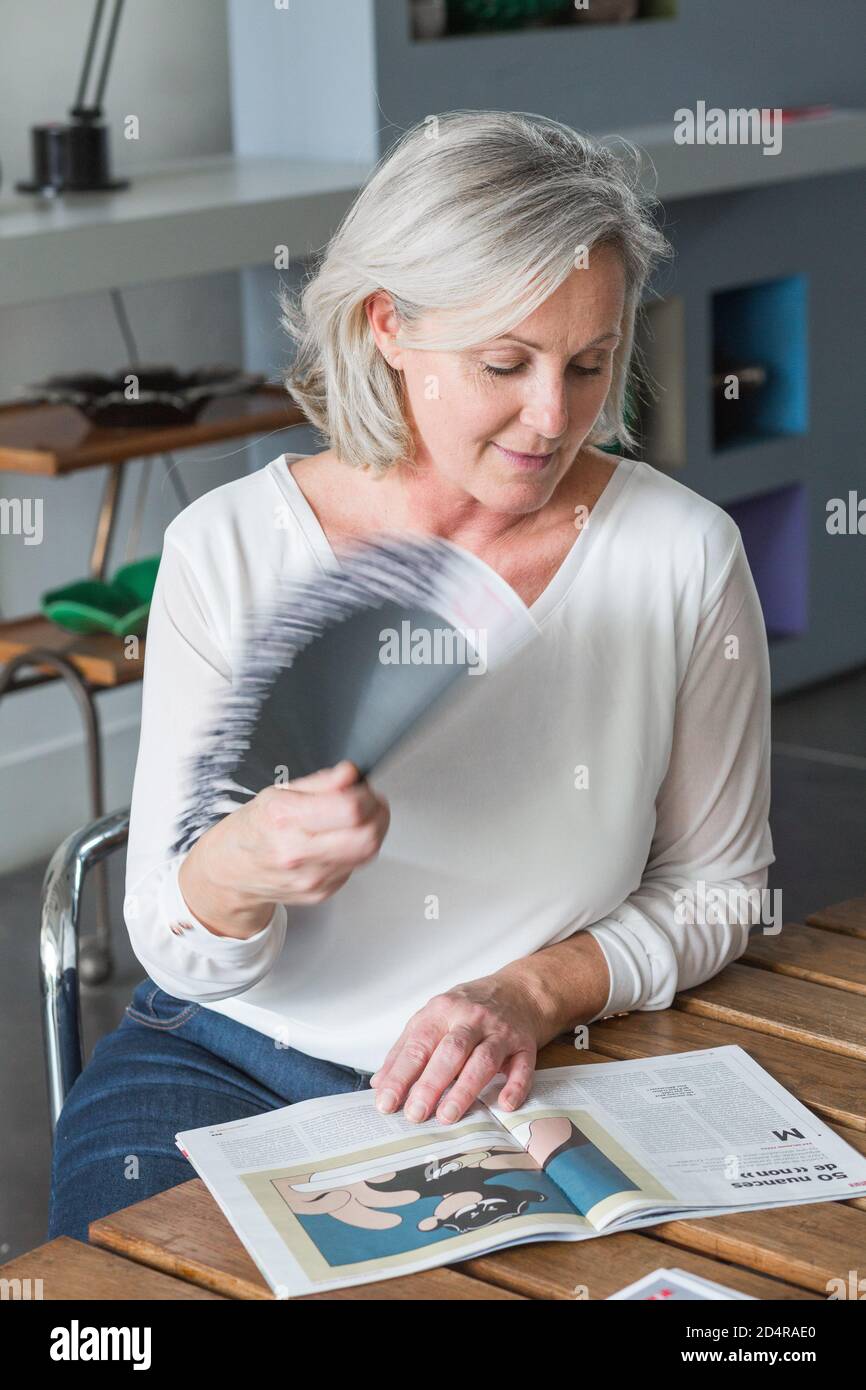 Ältere Frau kühlt ihr Gesicht mit einem Ventilator. Stockfoto