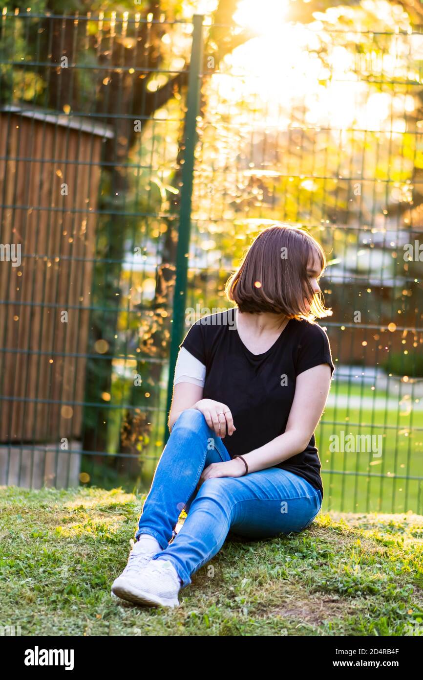 Junges Mädchen mit neuen kurzen Frisur sitzt im Park Mit schönem Hintergrund Stockfoto