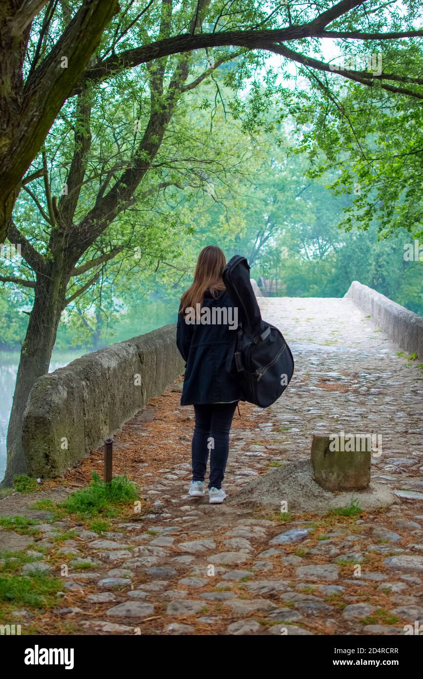Junges Mädchen tragen Gitarrentasche beim Gehen allein in naure Stockfoto