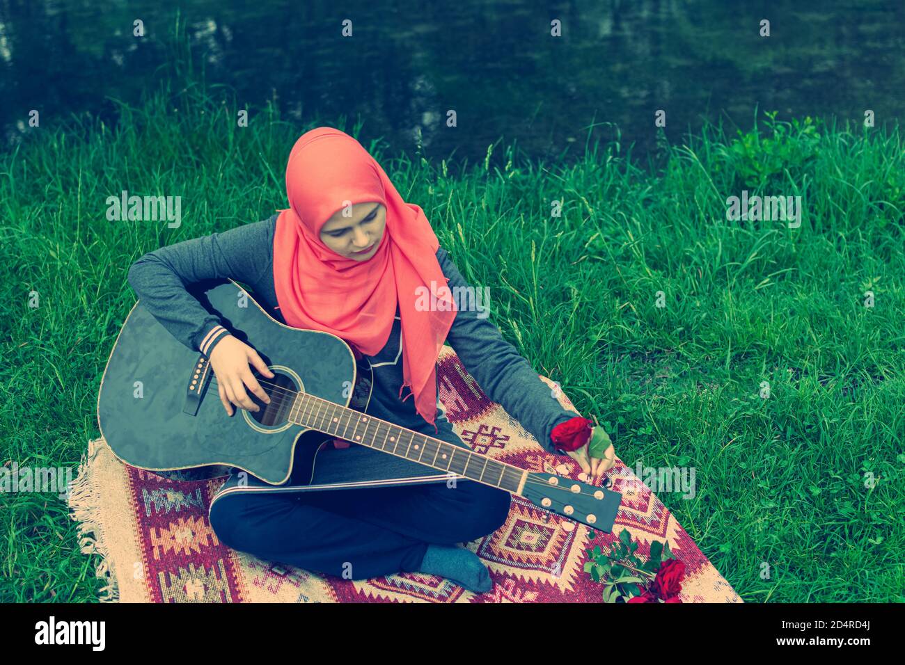 Junge muslimische Mädchen hält Gitarre und dekorieren es mit roten Rose Stockfoto