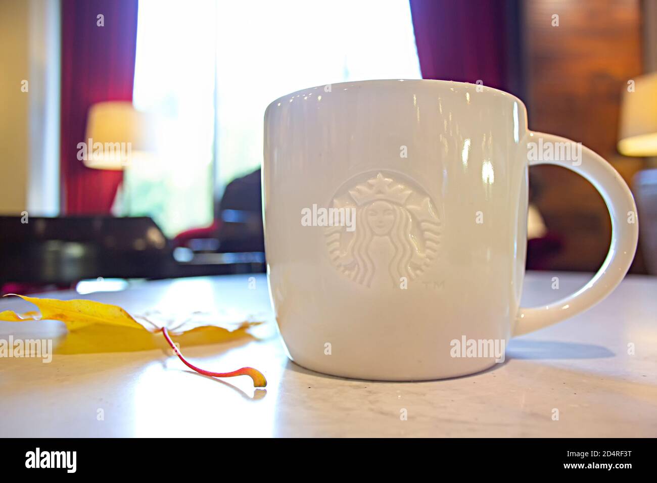 Saint-Petersburg, Russland - 03. OKTOBER 2020: Starbucks Kaffeetasse auf einem Kaffeetisch und ein gelbes Herbstahornblatt Stockfoto