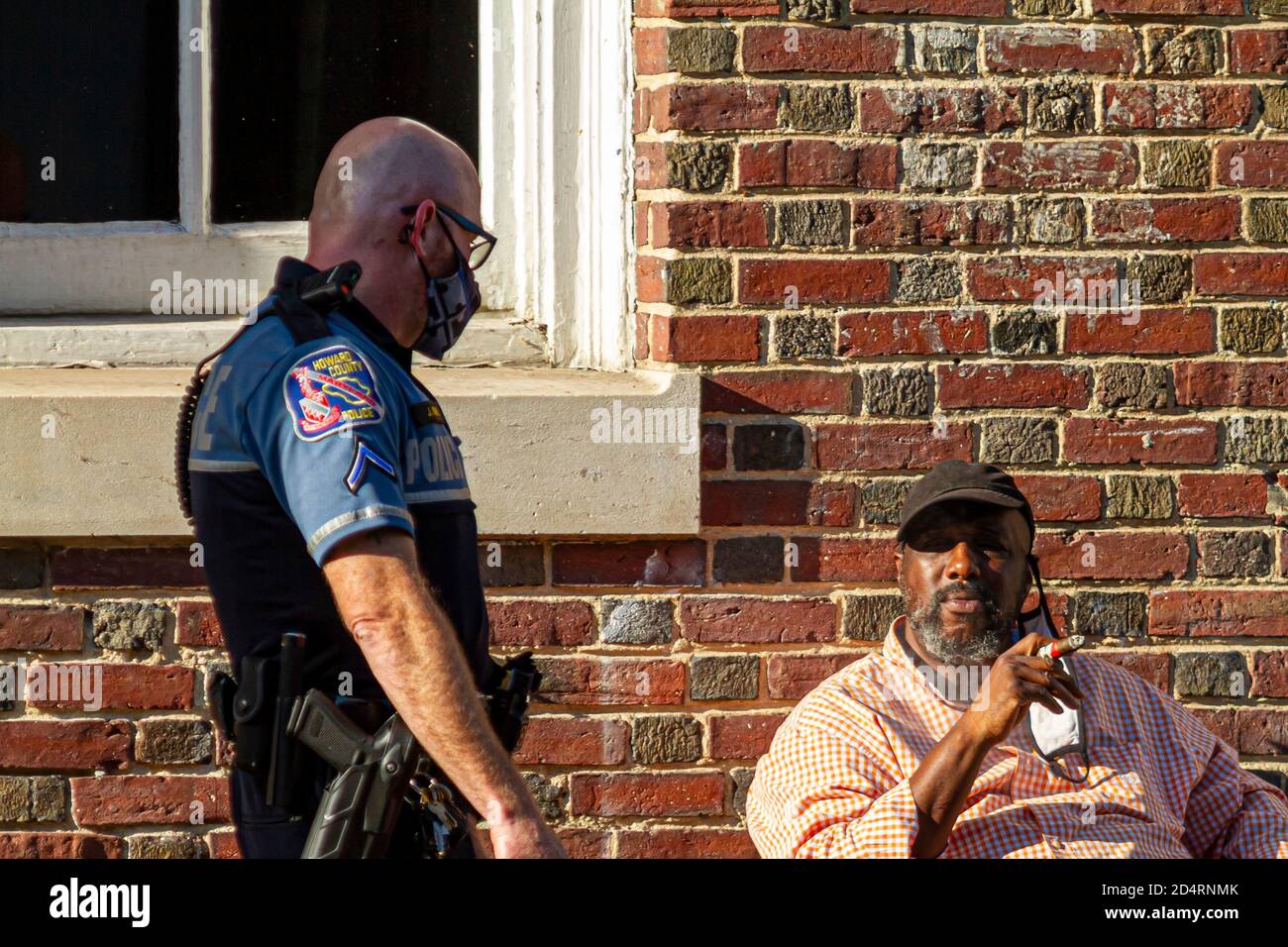 Ellicott City, MD, USA 10/07/2020: Ein weißer Polizist mit rasierten Kopf, der kurze und T-Shirt-artige Uniform und Gesichtsmaske trägt, spricht mit Stockfoto