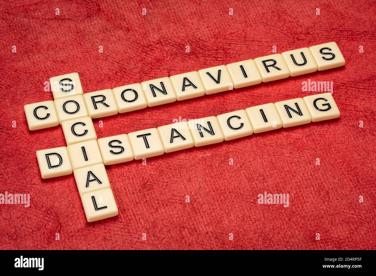 Coronavirus und soziale Distanzierung - Kreuzworträtsel in Elfenbeinbuchstaben gegen texturiertes Papier, covid-19 Pandemiekonzept Stockfoto