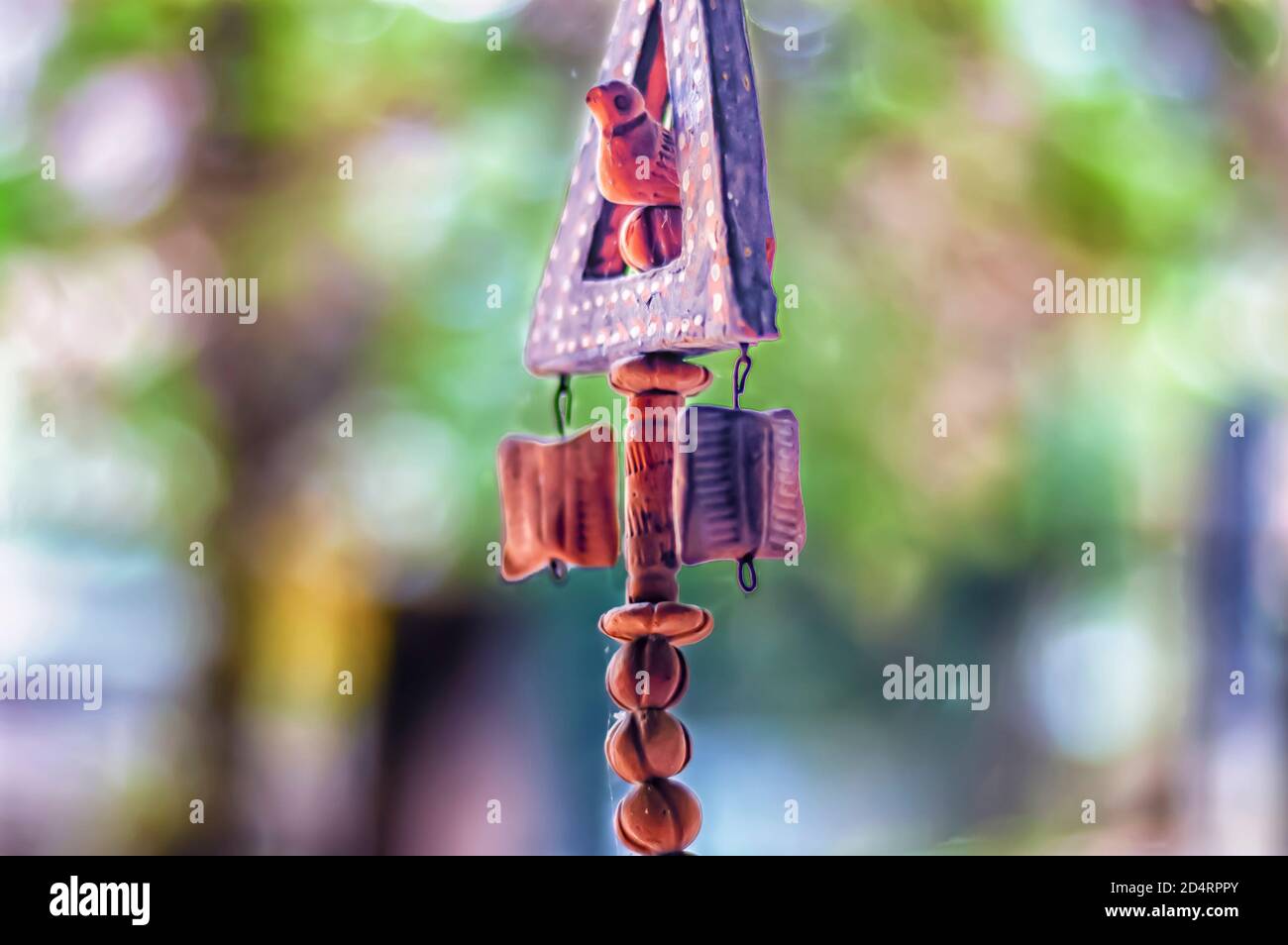 Ein Keramik-/Terrakotta-Gartenartefakt, das Tonkugeln und einen Tonvogel enthält, wird durch eine Schnur in der Luft aufgehängt. Stockfoto