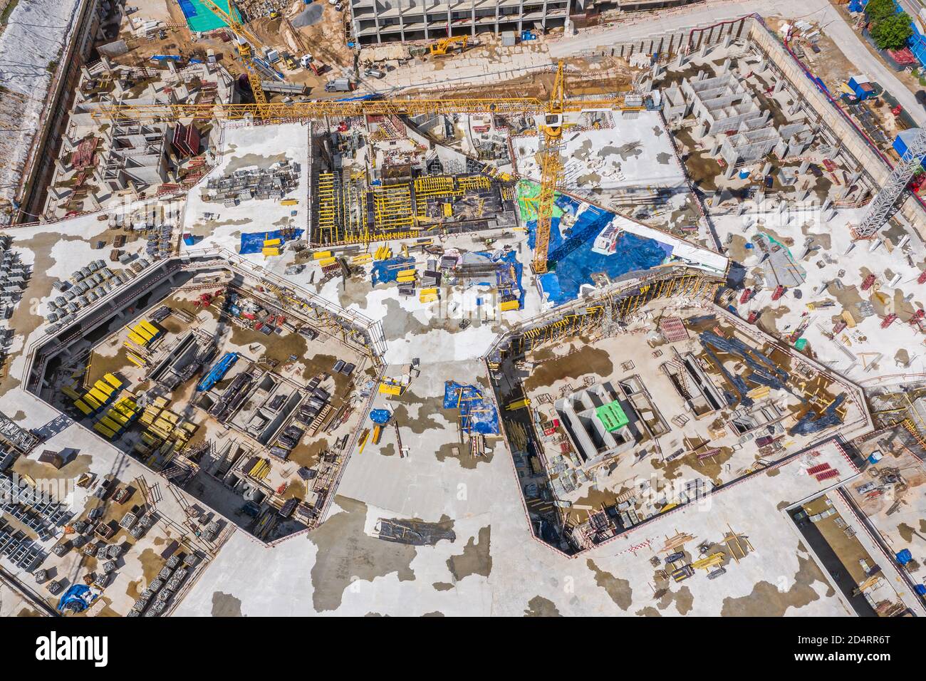 Aerial Draufsicht auf Gebäude mehrstufigen Fundament in der Stadt Baustelle. Hohe Turmdrehkrane und schwere Maschinen arbeiten Stockfoto