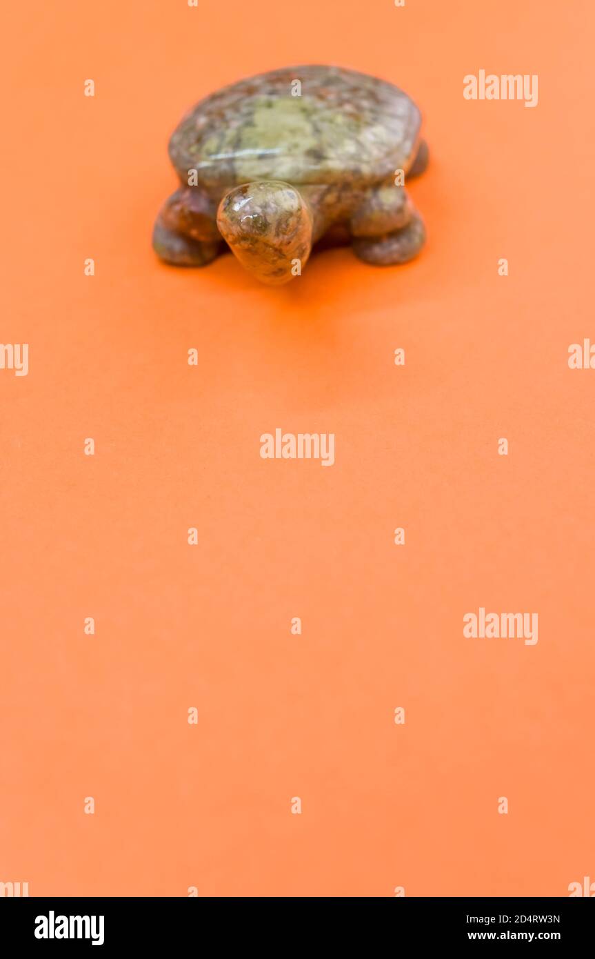 Vertikale Aufnahme einer braunen Schildkrötenstein Figur isoliert auf Ein orangefarbener Hintergrund Stockfoto