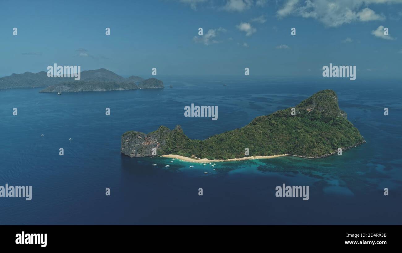 Tropic Island in Ocean Bay Luftbild. Boote und Schiffe im Hafen. Tropischer Wald auf der bergigen Insel Palawan, Philippinen. Epische blaue Meereslandschaft mit Wassertransport in filmischer Drohne mit sanftem Licht Stockfoto
