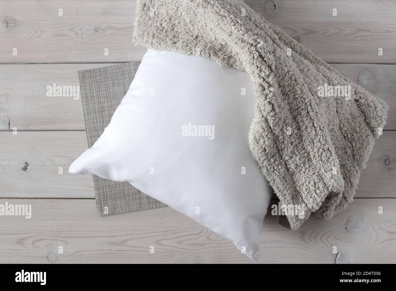 Weißes Kissen und weicher, flauschiger Teppich auf der Holzoberfläche. Stockfoto