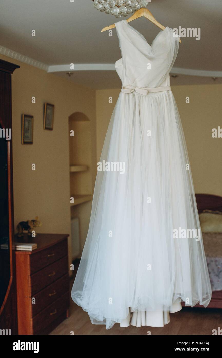 Schöne handgemachte Hochzeitskleid hängen auf einem Kleiderbügel in der Mitte des Raumes. Stockfoto