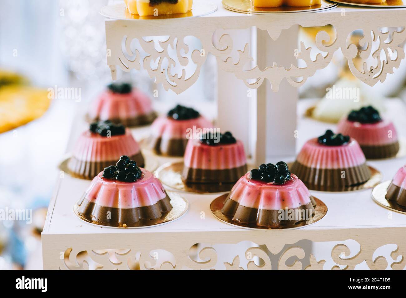 Hochzeitstorte mit bunten Cupcakes, Makronen, Kuchen, Gelee und Obst. Stockfoto