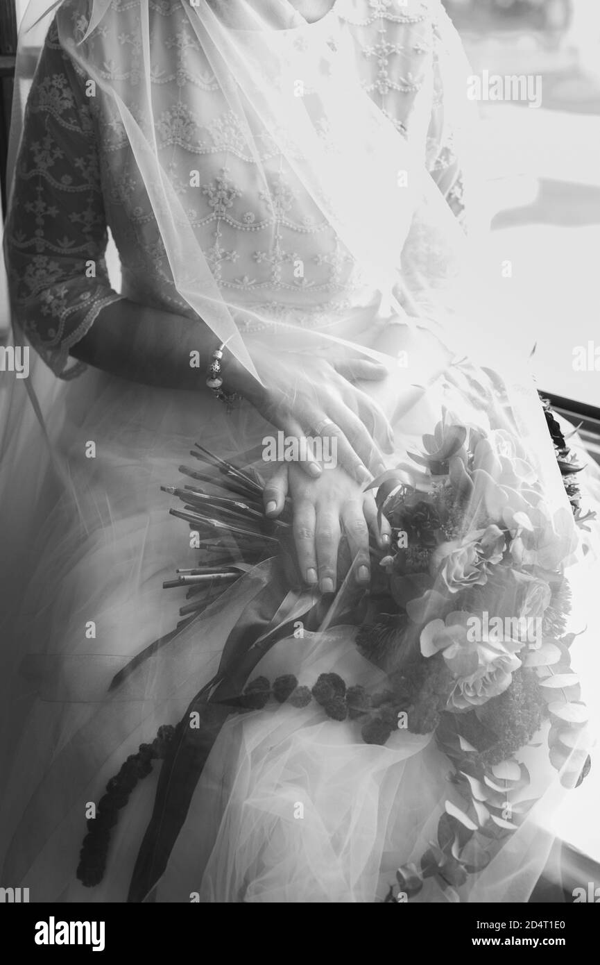 Zugeschnittenes Vintage schwarz-weißes Bild einer Braut mit einem Blumenstrauß in den Händen unter einem Schleier. Stockfoto