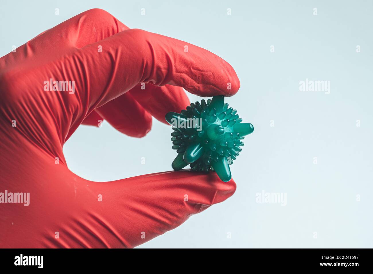 Hand in einem medizinischen Handschuh hält ein abstraktes Virus. Stockfoto