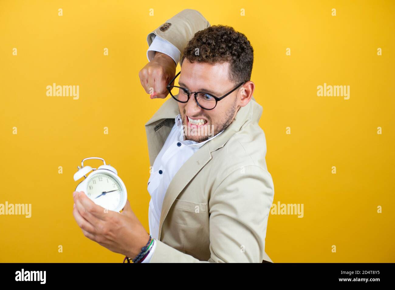 Junge gut aussehende Geschäftsmann tragen Anzug über isolierten gelben Hintergrund wütend, Stanzen der Uhr Stockfoto