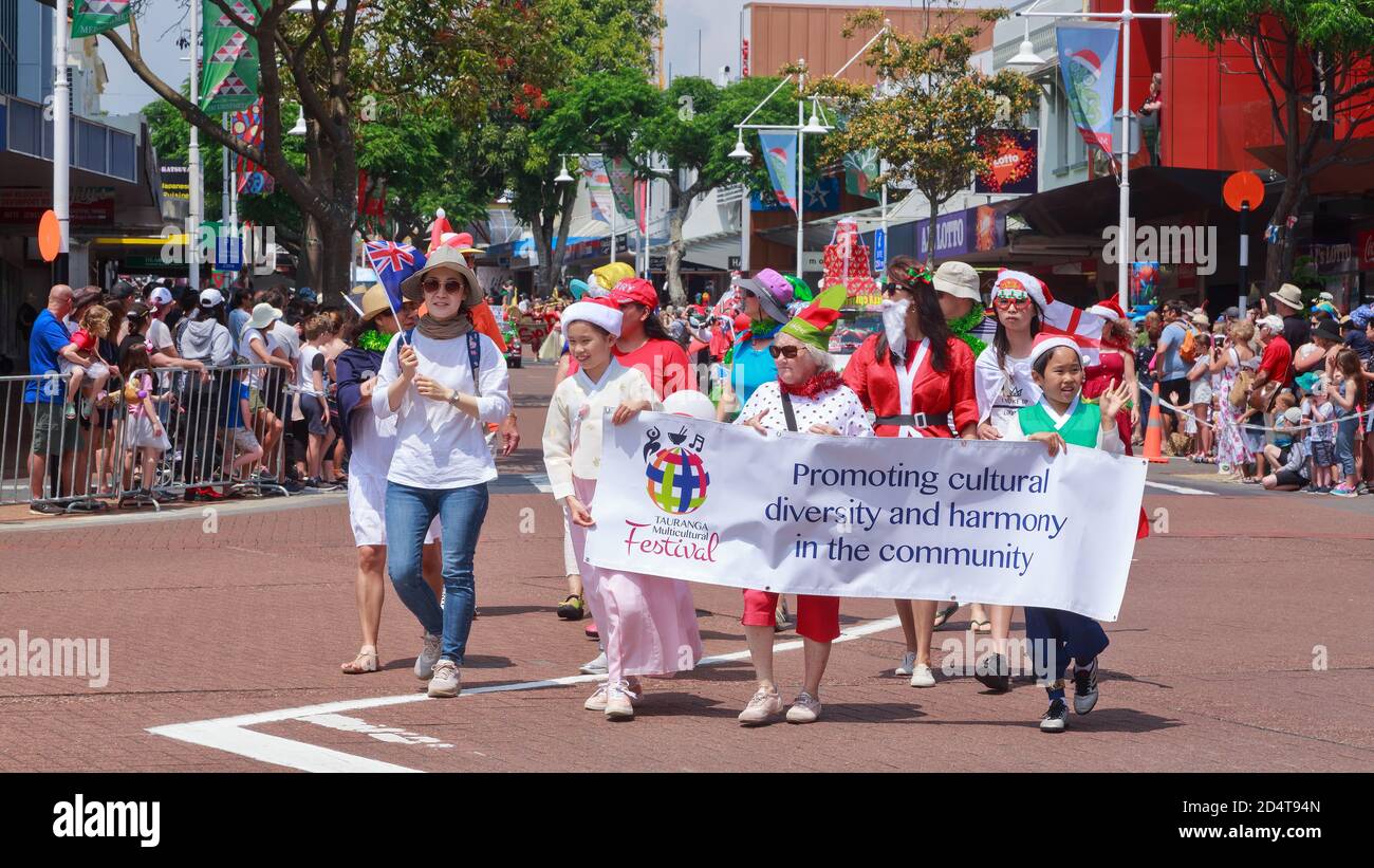 Mitglieder einer multikulturellen Gesellschaft marschieren in einer Parade mit einem Banner, das zu "kultureller Vielfalt und Harmonie" aufruft. Tauranga, Neuseeland, November 30 2019 Stockfoto