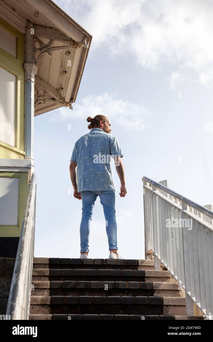 Bärtiger Mann in kurzen Sleevs und Jeans stehen auf Stufen Stockfoto