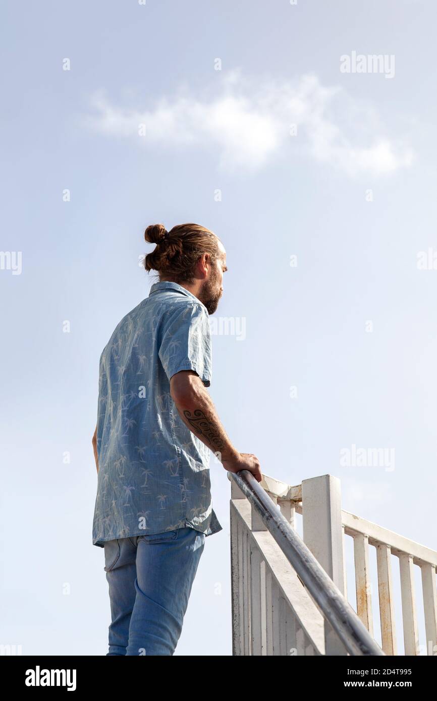 Bärtiger Mann in kurzen Sleevs und Jeans stehen auf Stufen Stockfoto