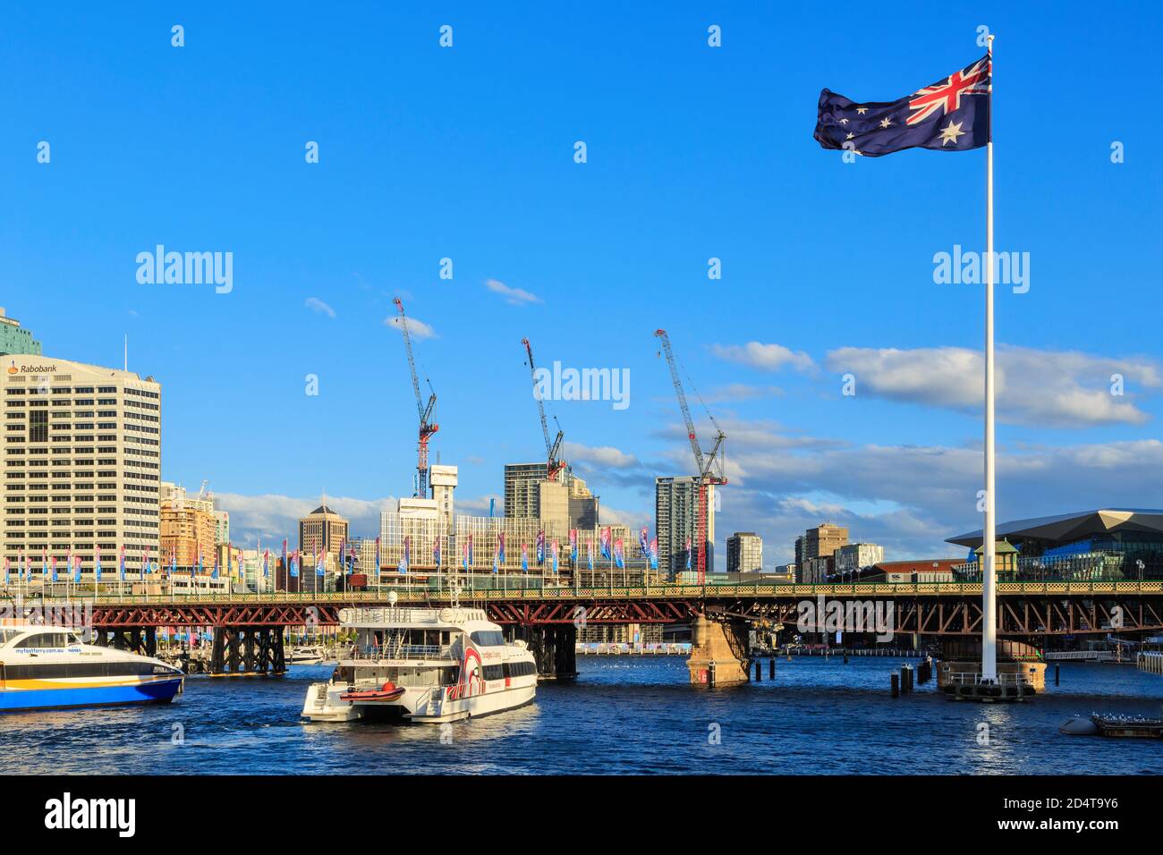 Neben der historischen Pyrmont Bridge in Darling Harbour, Sydney, Australien, fliegt eine riesige australische Flagge Stockfoto