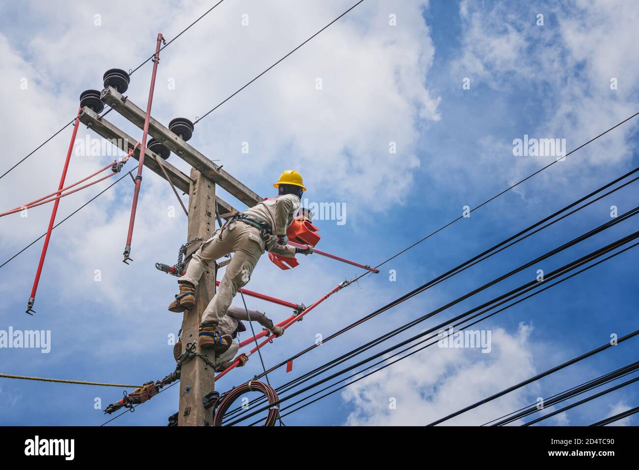 Der Lineman verwendet Krawattenstab, um den Krawattendraht zu schnitzen, der verwendet wird, um die elektrischen Drähte zu wickeln, die an dem beschädigten Hochspannungsisolator befestigt sind. Um sich vorzubereiten Stockfoto