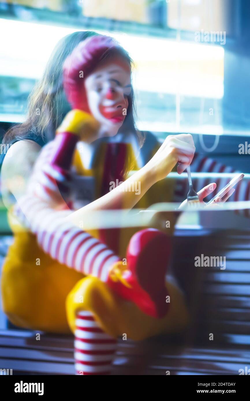 Bangkok, Thailand - 9. JULI 2019: Eine Ronald McDonald Statue und asiatische Frau Reflexion auf dem Spiegel des McDonald's Fast-Food-Restaurant. Bangkok. Stockfoto