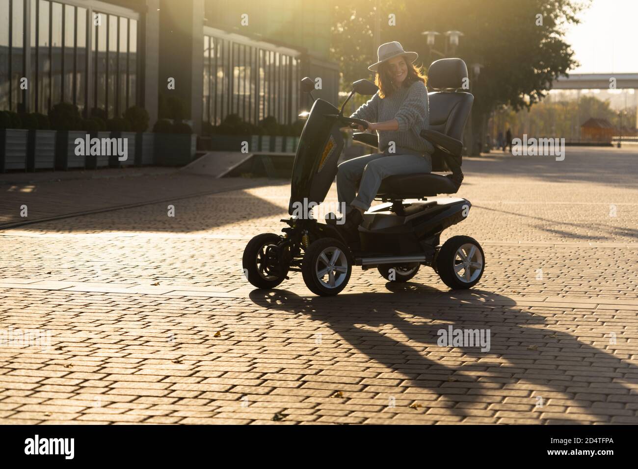 Frau Tourist Reiten ein vier Rad Mobilität Elektroroller auf einer Stadtstraße. Stockfoto