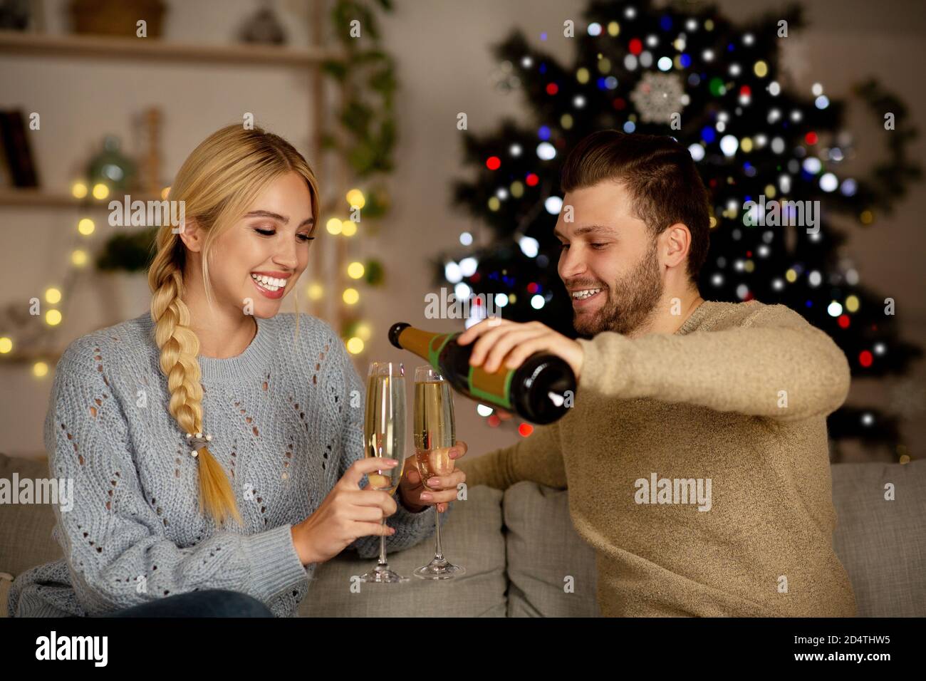 Junges Paar, das Champagner trinkt und zu Hause gemeinsam das neue Jahr feiert Stockfoto