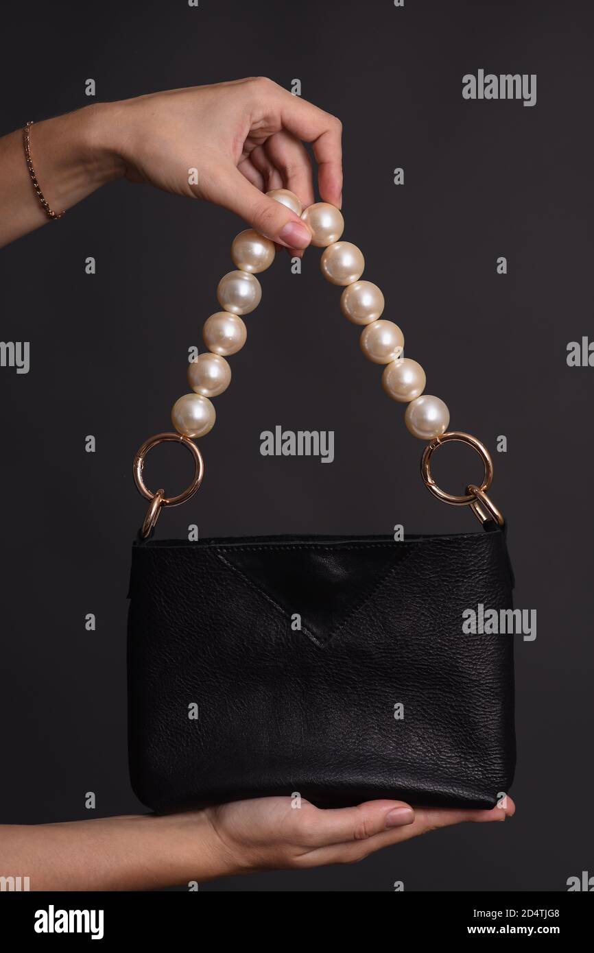 Eine Frauenhand hält eine Tasche am Griff aus großen Perlen. Der Trend von 2020. Stockfoto