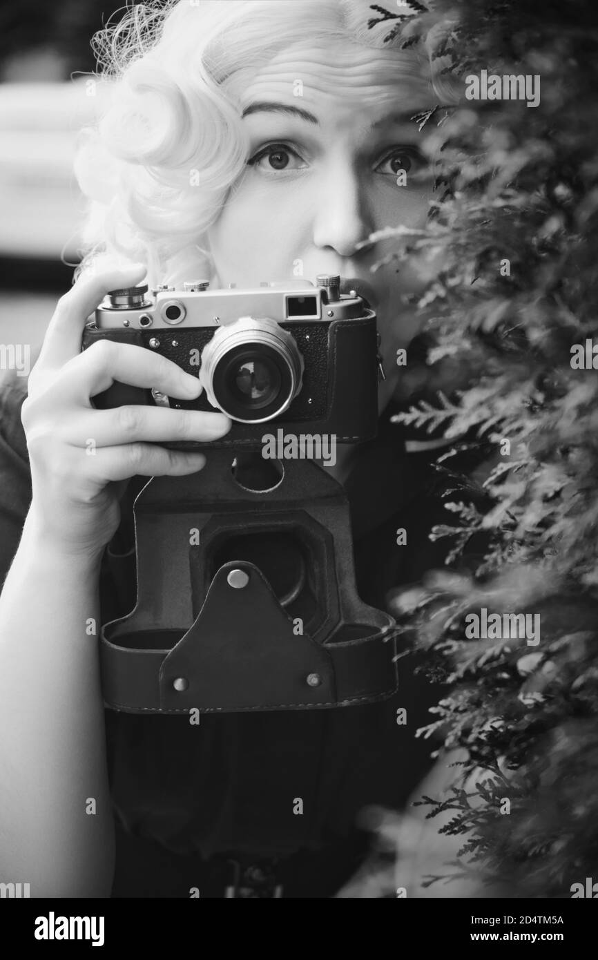 Junge blonde Frau mit alten Stil Fotokamera Aufnahme, monochrom Stockfoto