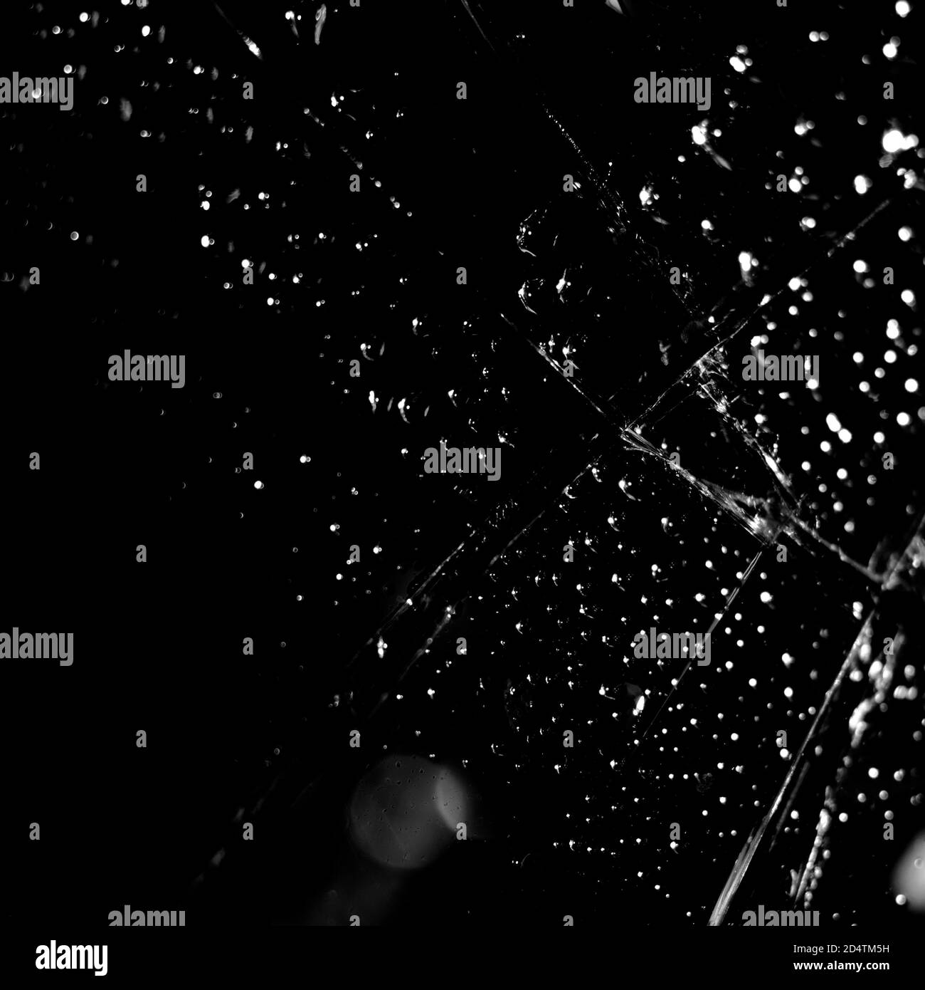 Gebrochener Glashintergrund in schwarz. Schwarzer minimalistischer Hintergrund mit Rissen auf dem Glas mit Wassertropfen. Stockfoto