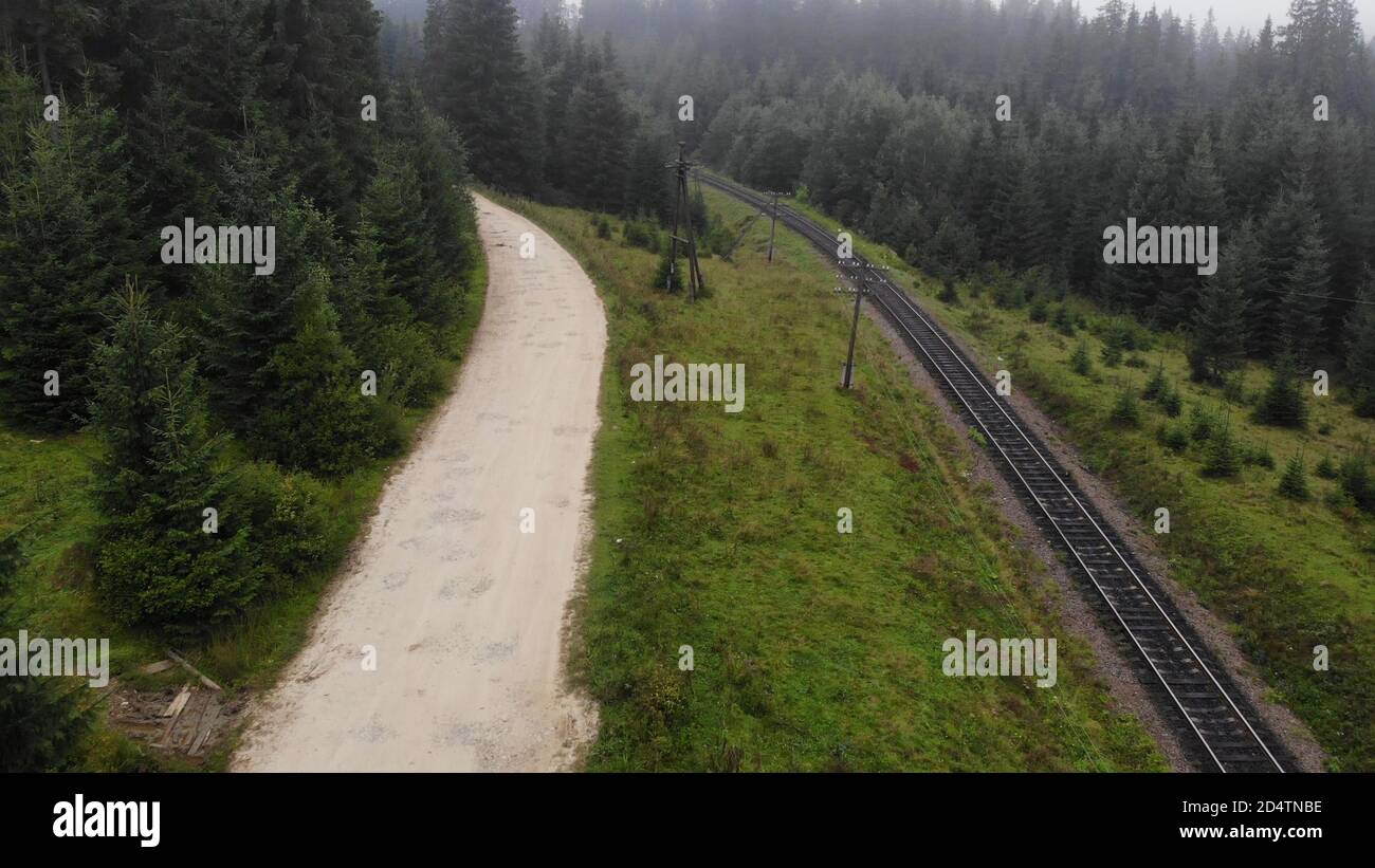 Die sandige Straße verläuft entlang der Eisenbahn. Stockfoto