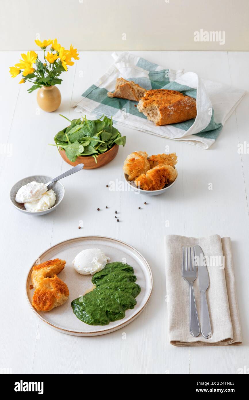 Hausgemachter, frischer, cremiger Spinat und pochiertes Ei mit gebratenem Brot. Leckeres gesundes Brunch oder Mittagessen. Stockfoto