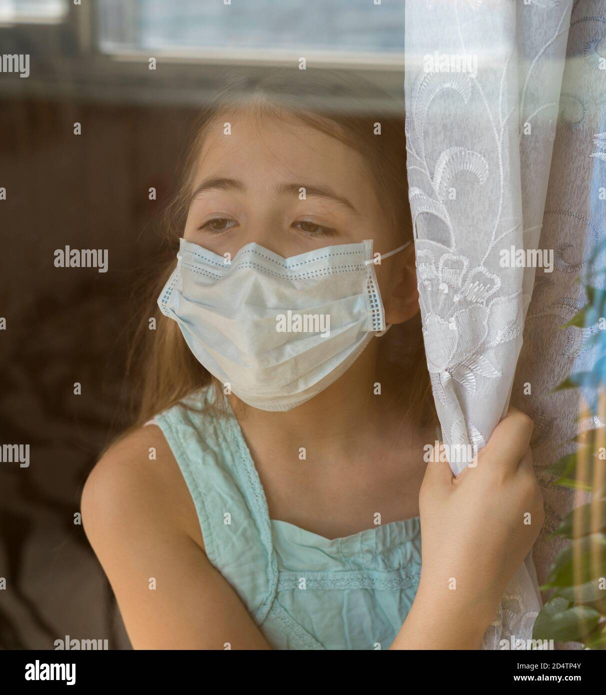 Bleiben Sie zu Hause Quarantäne Coronavirus Pandemie Prävention. Trauriges Kind in schützender medizinischer Maske schaut aus dem Fenster. Blick von der Straße. Prävention Epidemie. Stockfoto