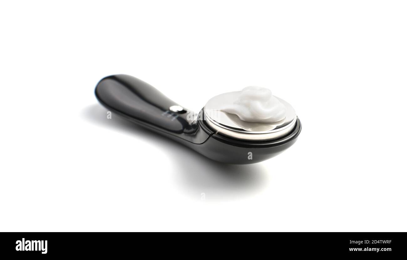 Nahaufnahme eines Massagegeräts mit weißer Creme auf weißem Hintergrund, Seitenansicht. Stockfoto