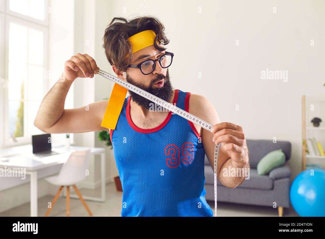 Fröhlicher bärtiger Mann in farbenfroher Sportbekleidung Messergebnis nach dem Sport Workout mit Maßband Stockfoto
