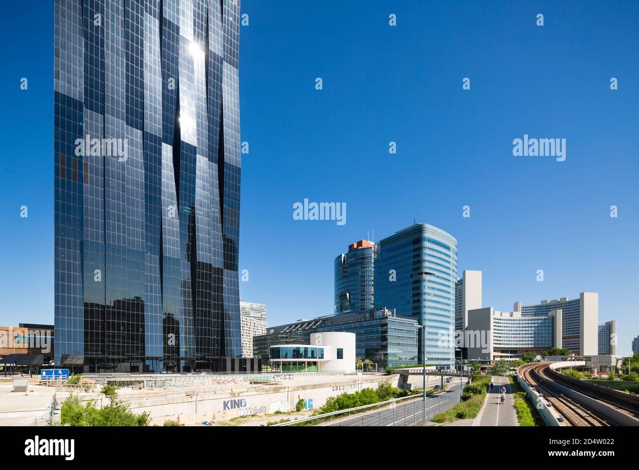 WIEN - 6. MAI: Das Vienna International Center und der Donau City Tower mit einigen Radfahrern, die sich am 6. Mai 2018 auf die Kamera zubewegen. Stockfoto