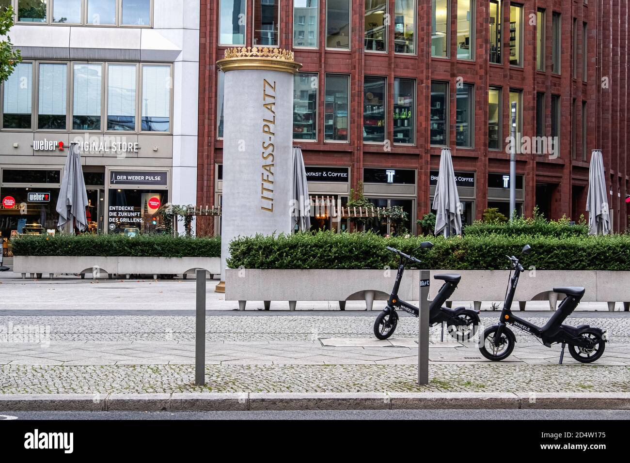 Litfass platz benannt nach Ernst Theodor Amandus Litfaß 1816-1874. Erfinder der Werbesäule in Mitte Berlin. Geparkte sitzende Räder E-Scooter Stockfoto