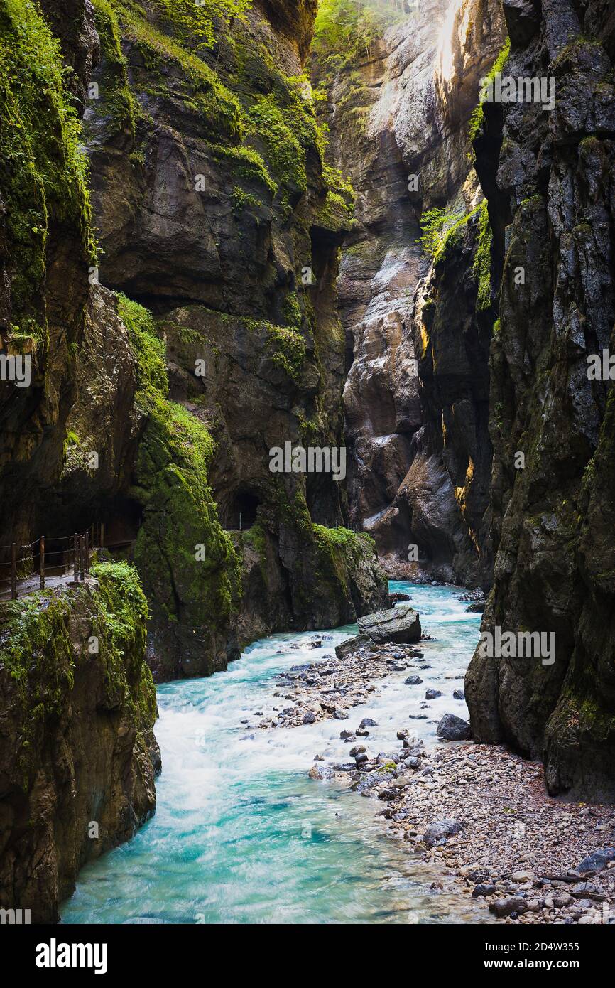Das Sonnenlicht scheint in die dunkle Schlucht. Stürmisch, Bergfluss fließt durch die Schlucht. Stockfoto