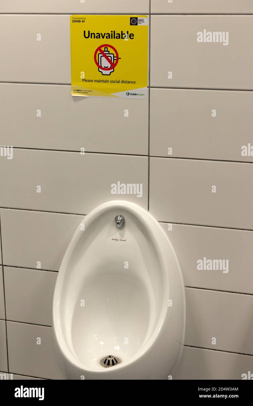 Soziale Distanzierung gelbe Zeichen in Männer oder Herren Toilette und Urinal nicht in Gebrauch aufgrund Covid 19 Pandemie auf dem Dublin Airport Ireland Europe. Stockfoto