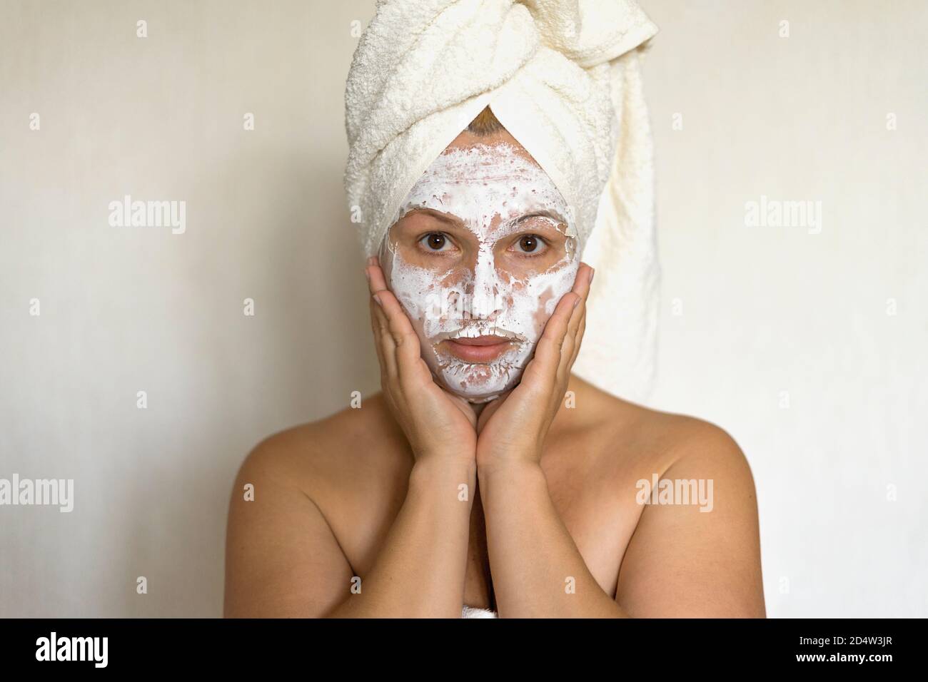 Frau auf einem weißen Hintergrund sauberes Gesicht Creme auf dem Gesicht Handtuch im Haar auf dem Kopf Stockfoto