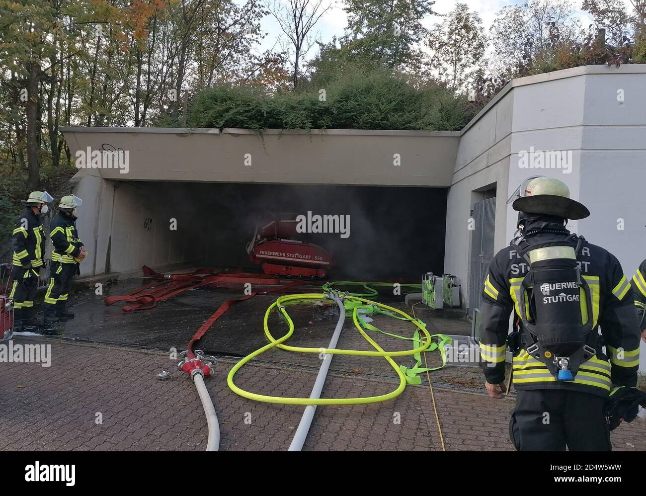 Stuttgart, Deutschland. Oktober 2020. Feuerwehrleute stehen am Eingang einer Tiefgarage, aus der Rauch ausströmt. Aufgrund der starken Rauchentwicklung war die Feuerwehr zunächst nicht in der Lage, die Garage im Wohngebiet zu betreten, wo mehrere Autos in Brand geraten waren. Die Brandursache im Landkreis Heumaden war zunächst unklar. Quelle: Andreas Rosar/dpa/Alamy Live News Stockfoto