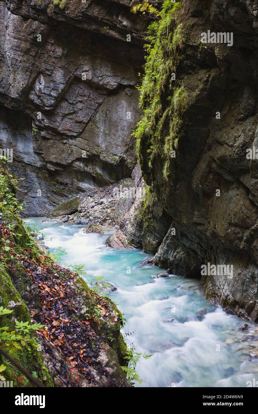 Wilder Gebirgsfluss mit klarem blauem Wasser fließt durch das offene Gebiet der Partnachklamm in Deutschland. Der schnelle Strom gleitet über die Felsen Stockfoto