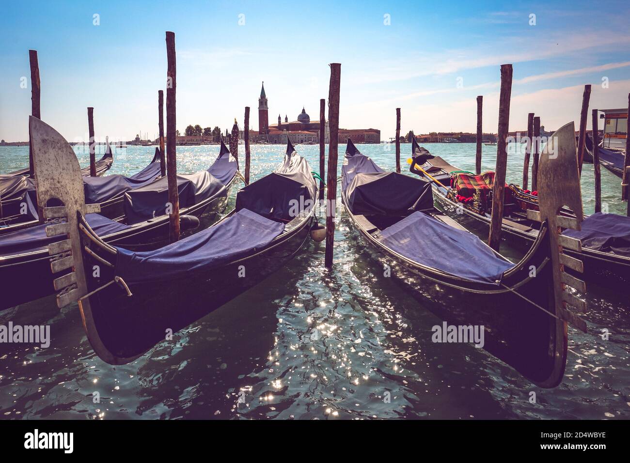 Typische venezianische Gondeln ankerten an der Lagune mit der Insel San Giorgio Maggiore und ihrem glockenturm im Hintergrund. Stockfoto