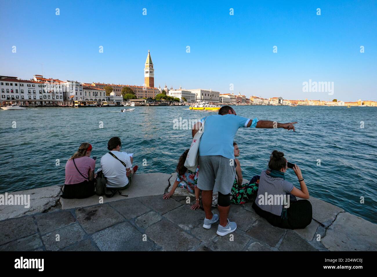 Touristen am Aussichtspunkt Punta della Dogana mit Blick auf die Lagune von Venedig, den Markusplatz und den berühmten Glockenturm Campanile. Stockfoto