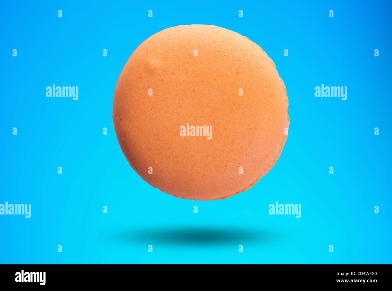 Orangefarbener Makronen, Cookie isoliert auf blauem Hintergrund. Stockfoto