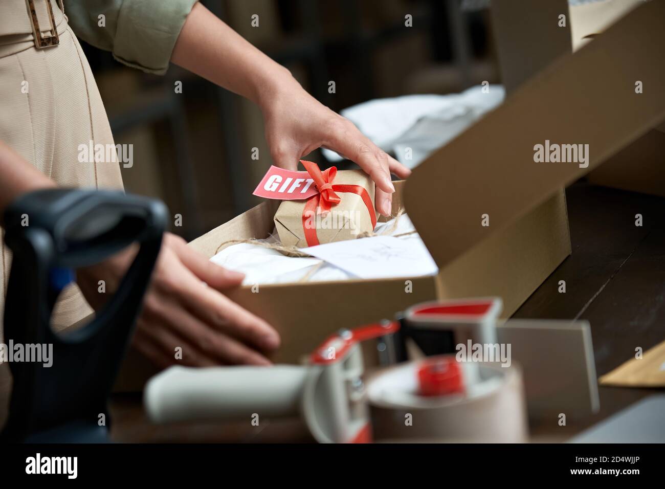 Weibliche Online-Shop Besitzer Verkäufer hält Geschenkpaket Post Versandkarton auf dem Tisch. Stockfoto