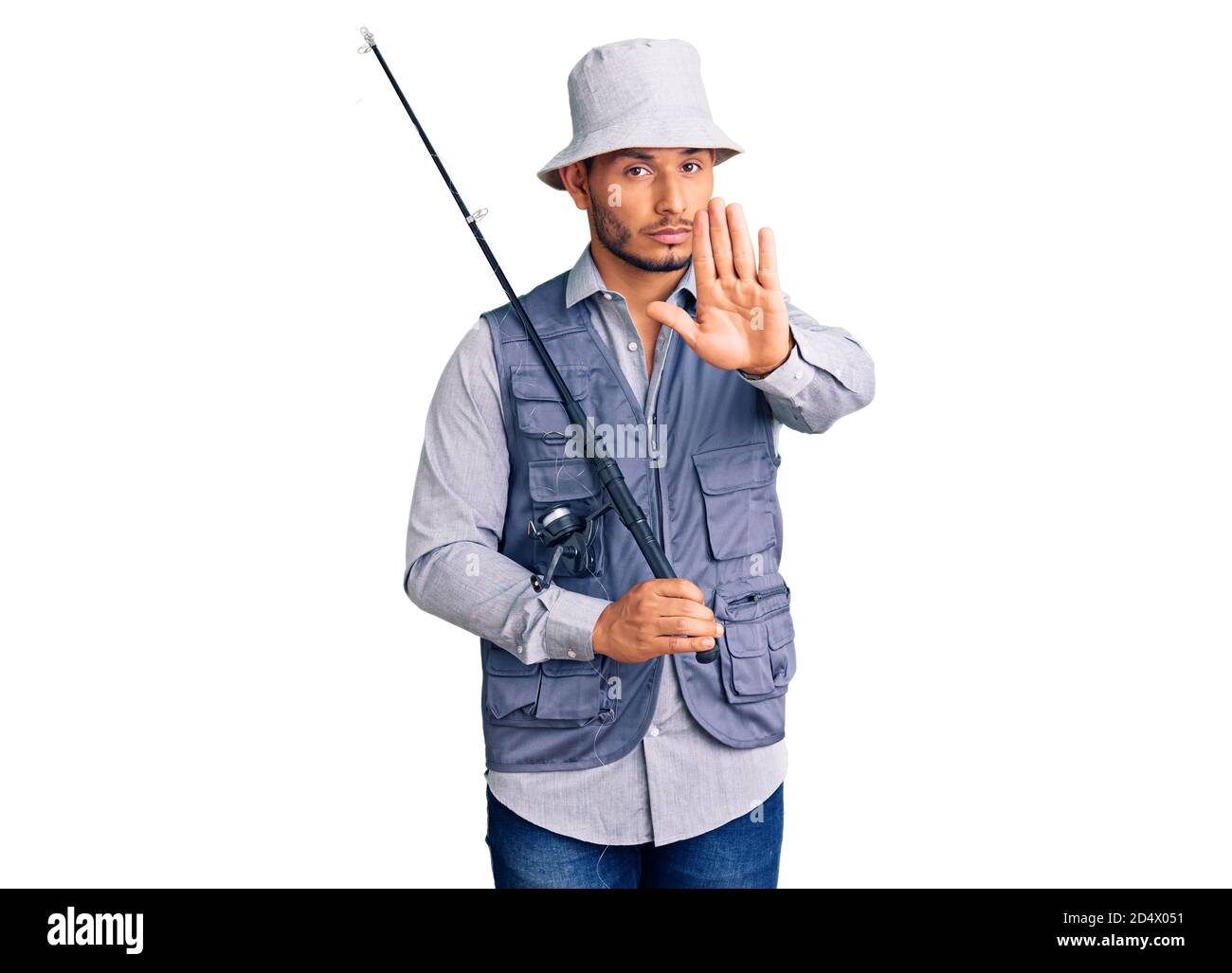 Schöner lateinamerikanischer junger Mann, der Fischerausrüstung mit offener Hand trägt und Stoppschild mit ernstem und selbstbewusster Ausdruck, Verteidigungsgeste tut Stockfoto