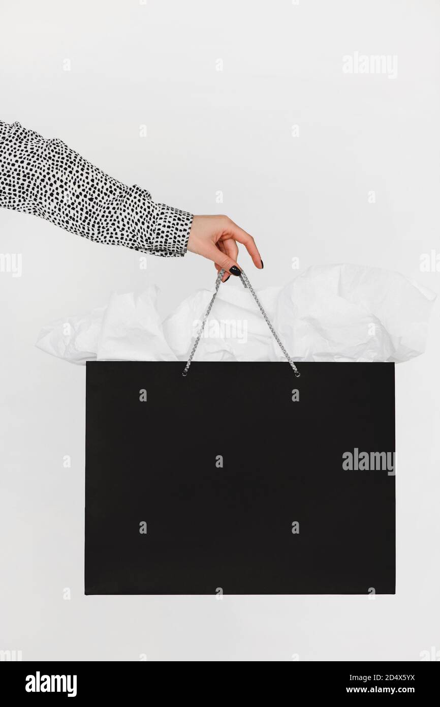 Beschnittenes Bild von Frau, die schwarze Einkaufstasche auf Weiß isoliert hält. Stockfoto